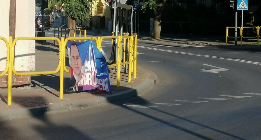 zdjęcie przedstawia baner reklamowy jednego z kandydatów na barierkach drogowych